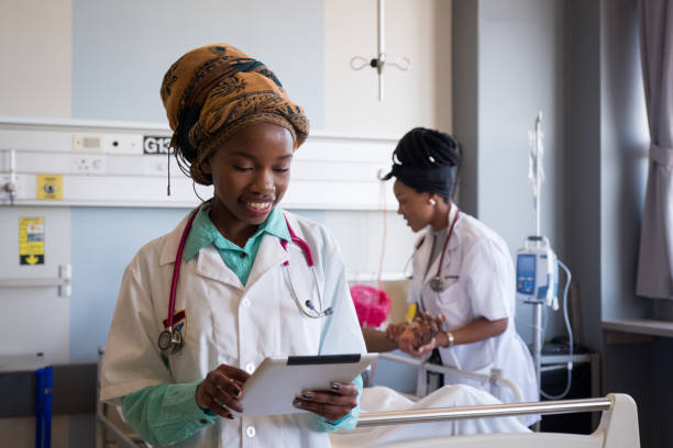 Revolutionizing healthcare for everyone: A young African healthcare worker uses a tablet to check the patients medical records