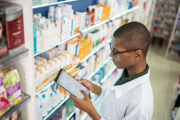 Revolutionizing healthcare for everyone: Young pharmacist checking the shelves with a digital tablet at a pharmacy