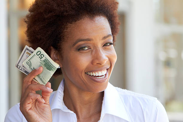 Revolutionizing healthcare for everyone: Female black doctor holds up money and smiles.