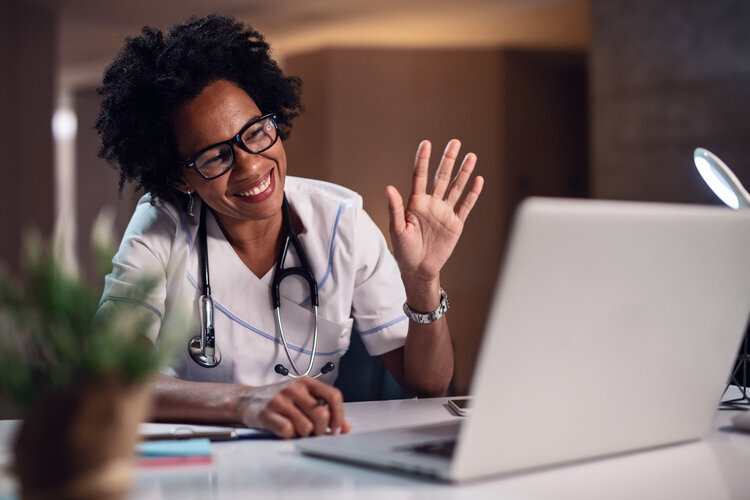 A doctor waving to a laptop screen - Telehealth