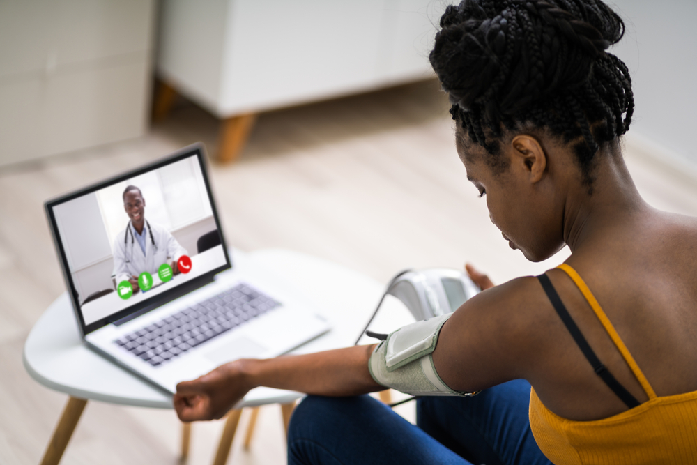 black female checking bp in front of a doctor via telehealth.